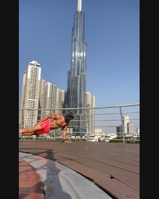 Outdoor side-plank training documented against a high-rise skyline in daylight.